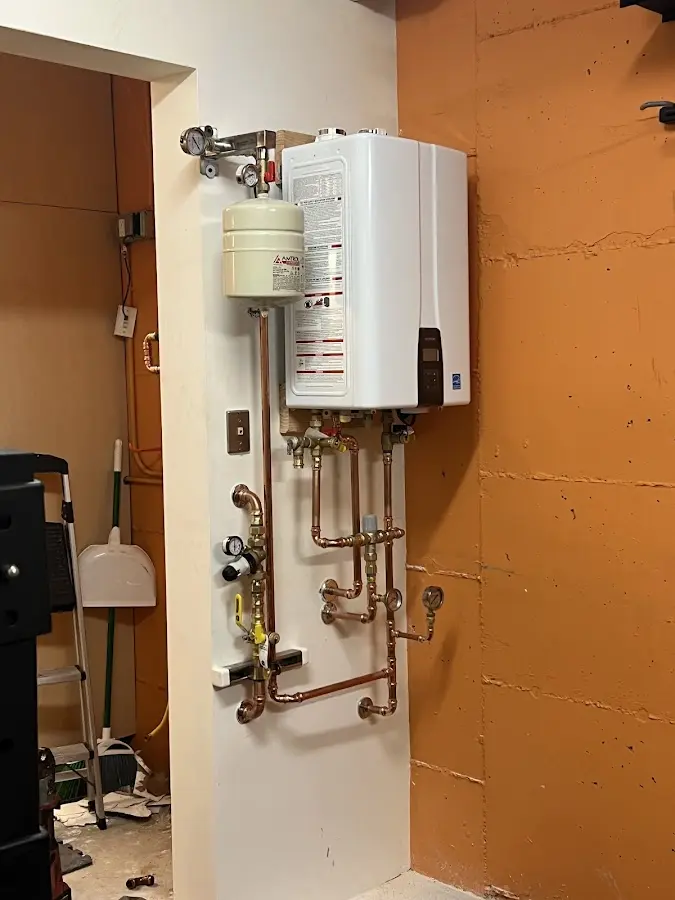 Plumbing technician inspecting water heater connections in Greentown